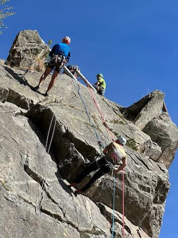 Grimpeurs en descente en rappel encordés avec un guide dans les Pyrénées-Orientales, activité d'escalade en montagne.