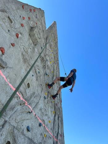 Homme en baudrier suspendu sur mur artificiel d'escalade d'Osseja, Pyrénées-Orientales