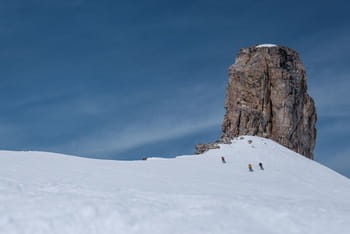 Groupe de skieurs freeride en train de escendre une pente hors piste enneigée.