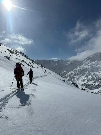 Ski de randonnée sous le soleil traversant une montagne enneigée dans les Pyrénées