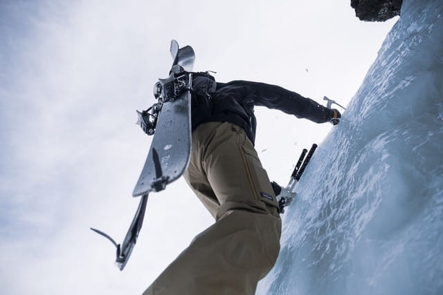 Entre le ski de randonnée et l'alpinisme, un skieur escaladant une cascade de glace avec piolet et crampons, et skis fixés à son sac à dos. Des sorties ski de rando / alpinisme accompagné d'un guide de haute montagne sans les Pyrénées au départ de Cerdagne / Capcir depuis font-romeu, les Angles, Formiguères, Porté Puymorens, Cambre d’aze ...