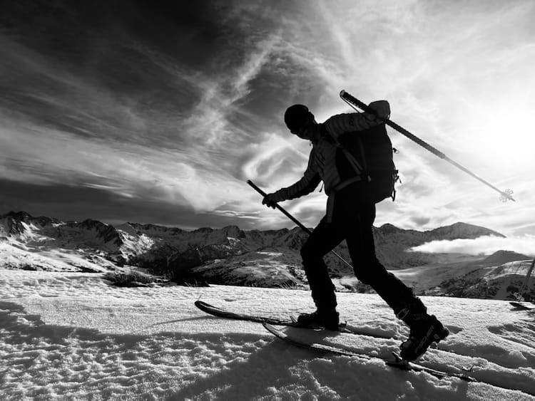 Skieur de randonnée posant face à l'objectif en position de montée, avec équipement complet de ski dans le cirque de Pessons en Andorre. Des sorties ski de rando / alpinisme accompagné d'un guide de haute montagne sans les Pyrénées au départ de Cerdagne / Capcir depuis font-romeu, les Angles, Formiguères, Porté Puymorens, Cambre d’aze ...