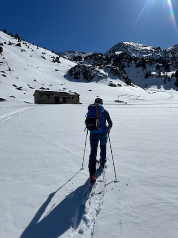 Un skieur pratiquant le ski de randonnée, dans les pyrénées, avec un guide de haute montagne, dans un décor enneigé et un ciel bleu, se dirigeant vers le Pic de Mortiers que l'on voit au loin. Départ en Cerdagne / Capcir depuis font-romeu, les Angles, Formiguères, Porté Puymorens, Cambre d’aze.