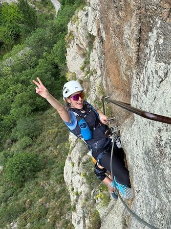 Participante joyeuse accrochée au câble de la via ferrata dans les Pyrénées