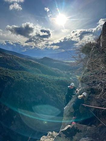 Pratiquant via ferrata sous soleil, encordé, vue sur forêt, Pyrénées, Font-Romeu, Sensations Pyrénées.