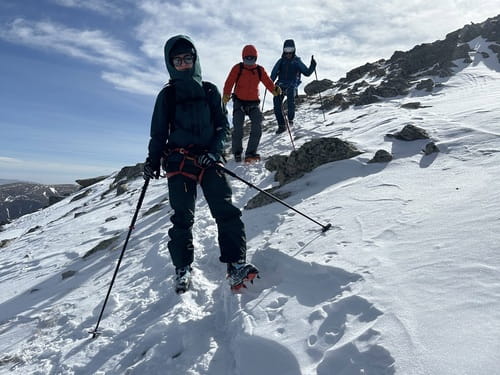 Trois alpinistes encordés, équipés de baudriers et de crampons, redescendant le sommet de la Tosseta de Valcivera en Espagne, encadrés par un guide de haute montagne, lors d'un raid à ski à travers l'Andorre depuis Grandvalira-Grau Roig.