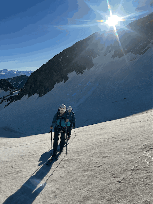 Montée vers l'Aneto en ski de randonnée sous le soleil, accompagné d'un guide.