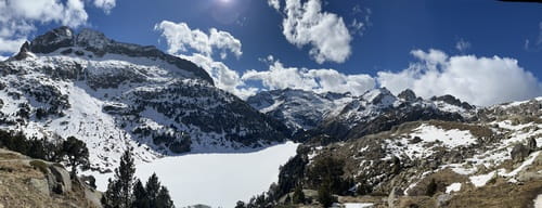 Paysage majestueux des Encantats dans le Parc National d'Aigüestortes i Estany de Sant Maurici, Espagne, avec vue sur un lac gelé encadré de sapins, sommets enneigés alentour, découvert lors d'un raid à ski de randonnée avec guide de Sensations Pyrénées.