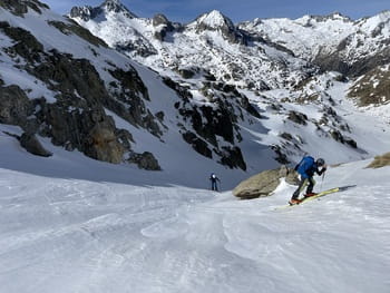 Deux skieurs en train de monter une pente raide en ski de randonnée, se préparant à effectuer une conversion dans un paysage enneigé du parc des plus hauts sommets d'Aragon, Pyrénées.