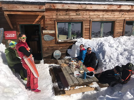 Groupe en pause lors d'une sortie en ski de randonnée au refuge des Camporells, savourant des boissons chaudes et des encas.