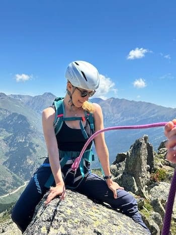 Alpiniste en baudrier encordée à cheval sur un rocher au sommet des Pyrénées Catalanes près de Font-Romeu. Alpiniste en baudrier encordée à cheval sur un rocher au sommet des Pyrénées Catalanes près de Font-Romeu.