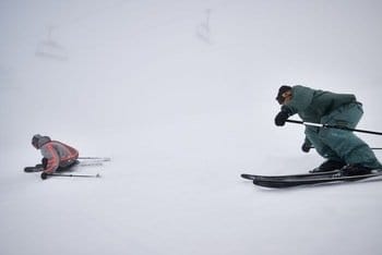 Deux skieurs en descente hors-piste, alignant les virages dans un paysage brouillé et immaculé de neige, avec un environnement entièrement blanc autour d'eux Deux skieurs en descente hors-piste, alignant les virages dans un paysage brouillé et immaculé de neige, avec un environnement entièrement blanc autour d'eux