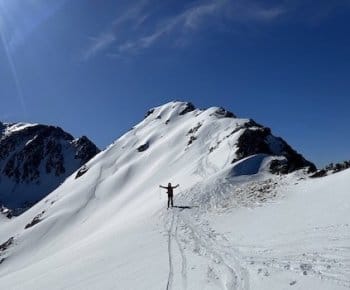 Skieur exultant en descente sous un ciel bleu, après ascension le long de l'arête du Pic de l'Homme Mort (2655 m) enneigé, dans un paysage ensoleillé des Pyrénées Catalanes, encadré par un guide de haute montagne Skieur exultant en descente sous un ciel bleu, après ascension le long de l'arête du Pic de l'Homme Mort (2655 m) enneigé, dans un paysage ensoleillé des Pyrénées Catalanes, encadré par un guide de haute montagne